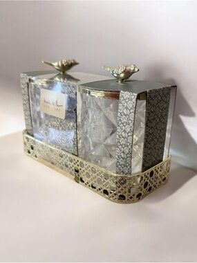 two-piece glass storage jar set with a gold bird lid and decorative tray.